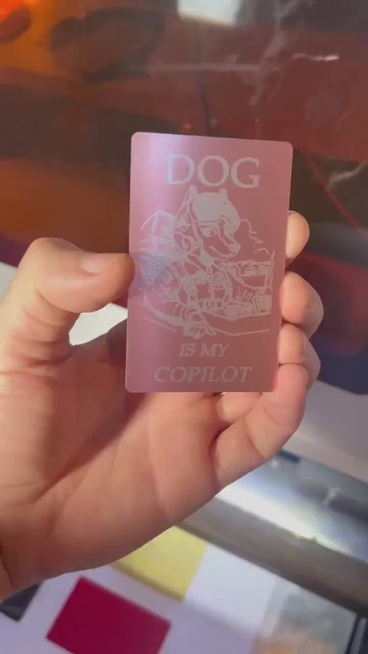 Close-up video of rose gold and silver anodized metal card rotating to show laser engraved dog is my co-pilot funny design and text