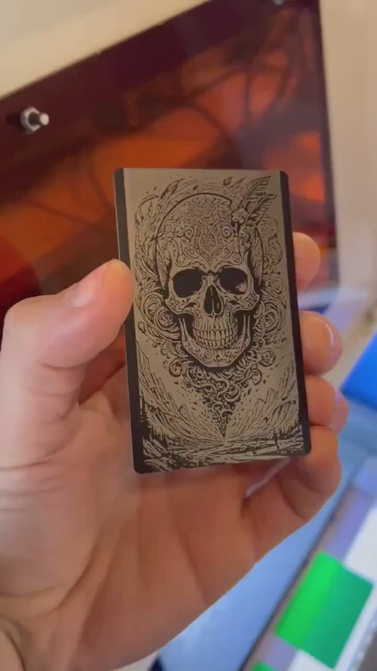 Hand holding a laser engraved illustration graphic card with surreal skull engraving art
