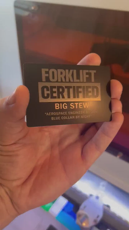 Close up video of hand holding a laser engraved metal gift card with Forklift Certified text, and personalized customer name and message engraved below