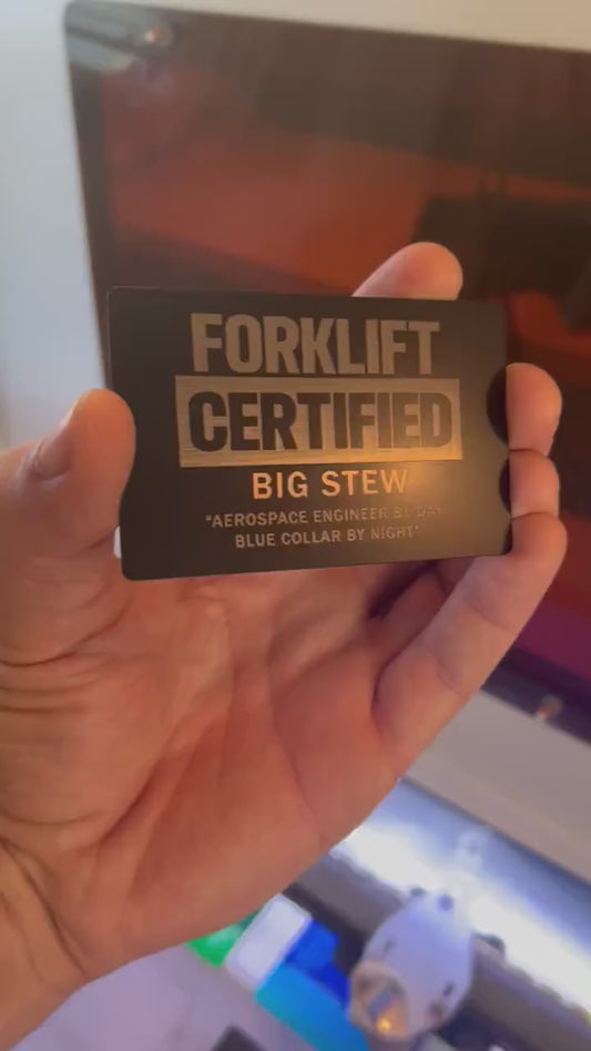 Close up video of hand holding a laser engraved metal gift card with Forklift Certified text, and personalized customer name and message engraved below