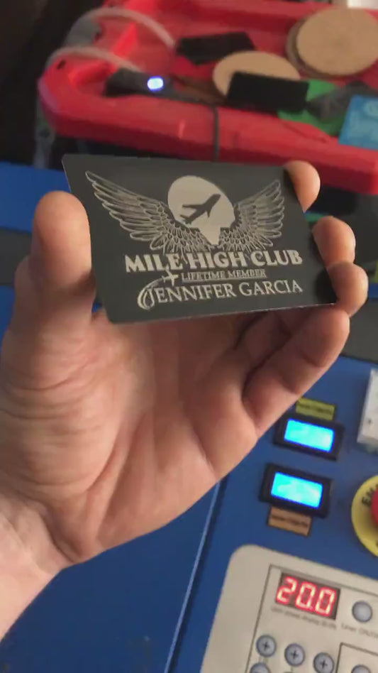 Close up video of hand holding a laser engraved metal keepsake funny gift card with Mile High Club: Lifetime Member and customer supplied personalized name engraving below in black/silver