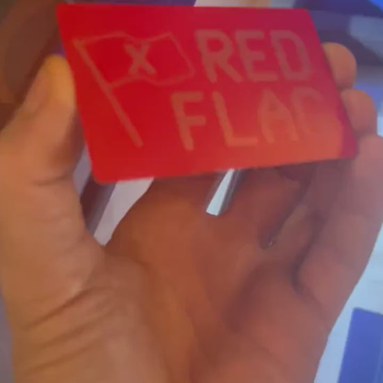 Close-up video of red/silver anodized metal Red Flag keepsake card rotating to show laser engraved design and typography