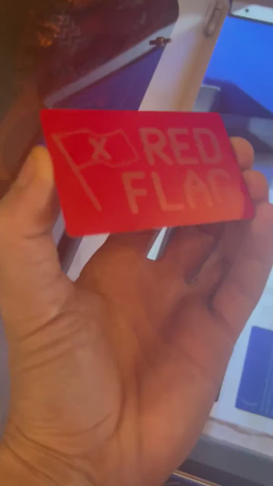Close-up video of red/silver anodized metal Red Flag keepsake card rotating to show laser engraved design and typography