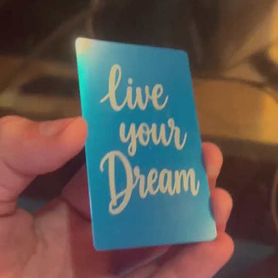 Detailed shot of engraved anodized metal keepsake card featuring “Live Your Dream” inspirational text design