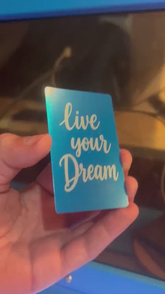 Detailed shot of engraved anodized metal keepsake card featuring “Live Your Dream” inspirational text design