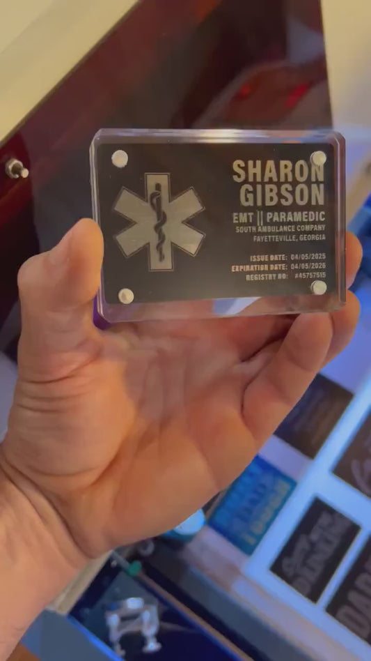Video of hand holding a metal laser engraved black/silver EMT business card with personalized contact information card shown in optional acrylic display case
