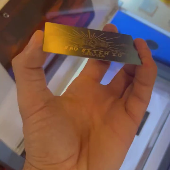 Close up video of hand holding a laser engraved metal friendsgiving gift card with bad bitch ID text and personalized name