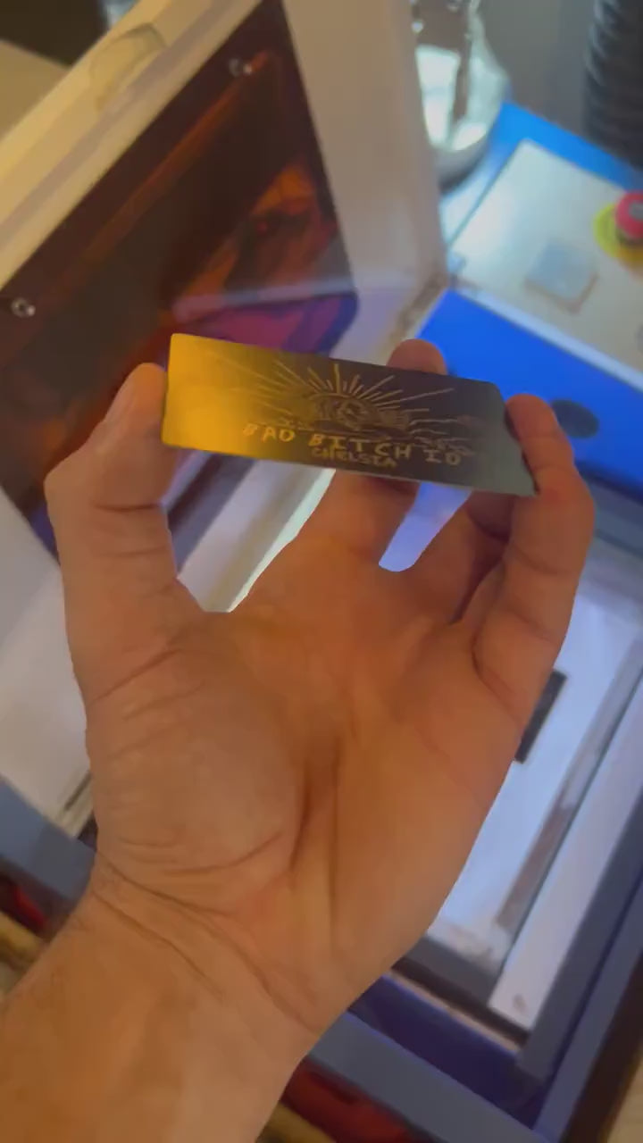 Close up video of hand holding a laser engraved metal friendsgiving gift card with bad bitch ID text and personalized name