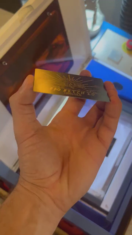 Close up video of hand holding a laser engraved metal friendsgiving gift card with bad bitch ID text and personalized name