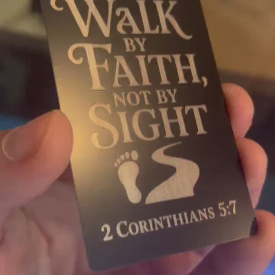 Showcasing a metal laser engraved keepsake card that reads Walk By Faith, Not By Sight, in stylish typography, with a foot step & path graphic, and bible reference for 2 Corinthians 5:7