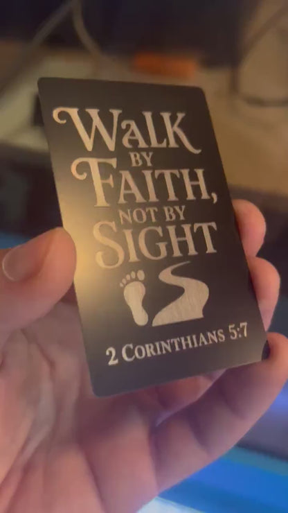 Showcasing a metal laser engraved keepsake card that reads Walk By Faith, Not By Sight, in stylish typography, with a foot step & path graphic, and bible reference for 2 Corinthians 5:7