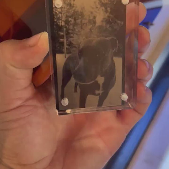 Hand holding laser engraved metal keepsake pet portrait card shown in optional acrylic display case