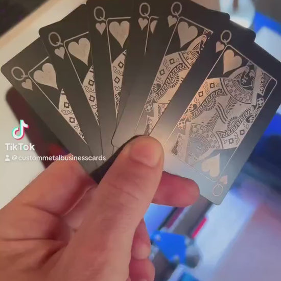 Close up video of hand holding 6 laser engraved metal playing cards with Queen of hearts designs shown in black/silver