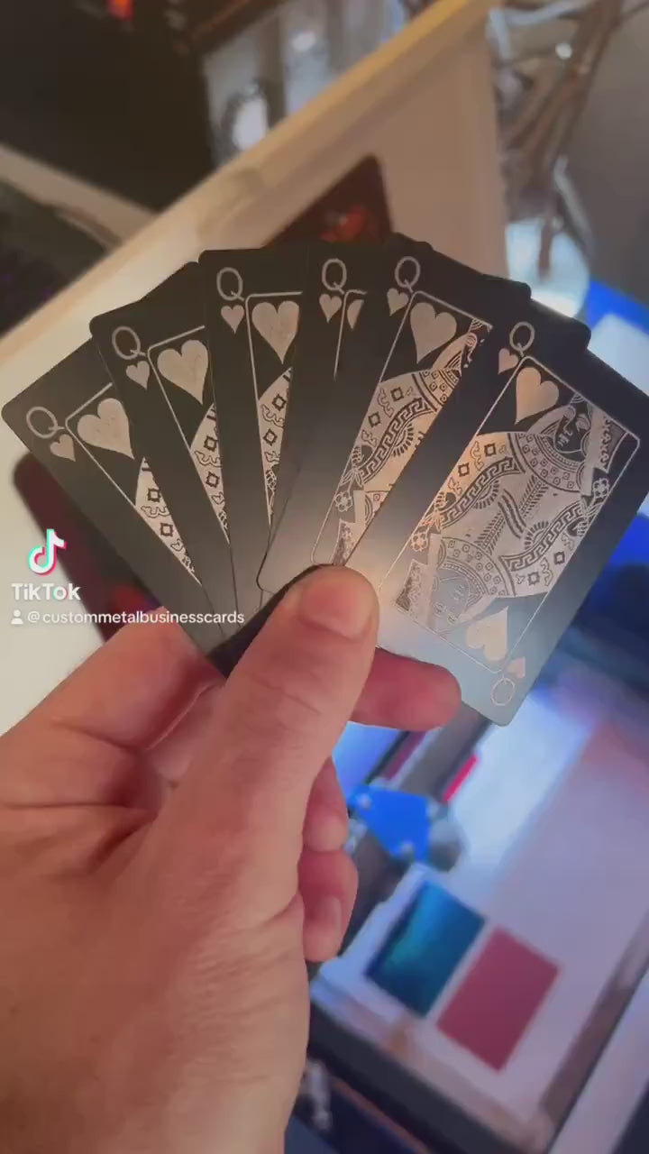 Close up video of hand holding 6 laser engraved metal playing cards with Queen of hearts designs shown in black/silver