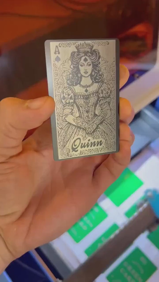 Hand holding a laser engraved personalized gift card with custom name engraved reading "Quinn", on top of our Lady Luck Ace of Spades poker illustration anodized aluminum gift card