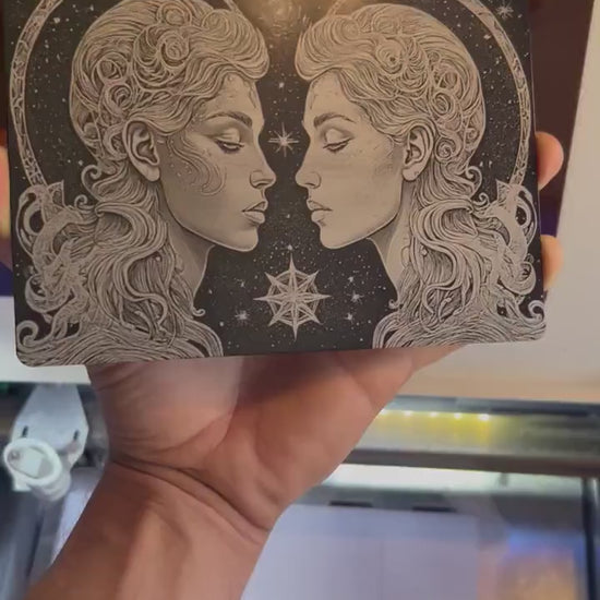 hand holding a metal 7x5 plaque with gemini twins laser engraving psychedelic artwork, rotating back and forth to show reflective qualities