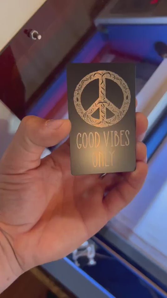 Video of engraved metal wallet card turning under light to show reflective finish and good vibes only with patterned hippie peace sign artwork