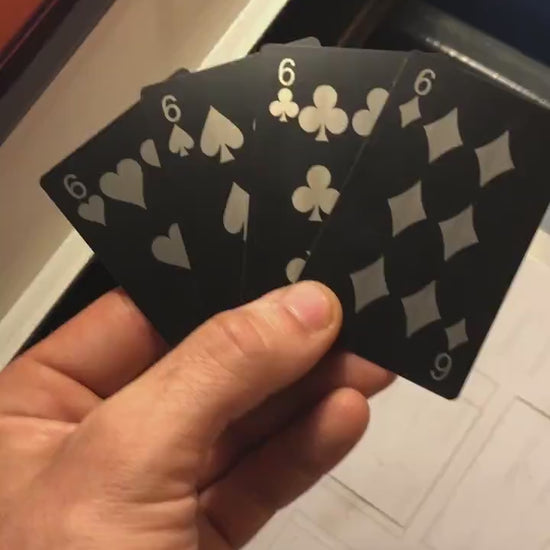 Close up video of hand holding 4 laser engraved metal playing cards with 6 of hearts, 6 of spades, six of clubs and six of diamonds cards