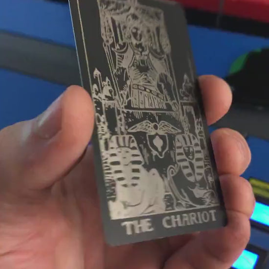 Hand holding a laser engraved metal tarot card with The Chariot design
