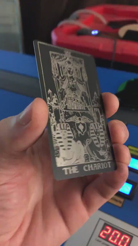 Hand holding a laser engraved metal tarot card with The Chariot design
