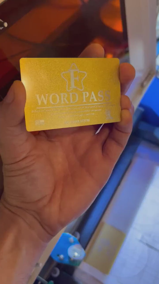 Laser engraved metal business card, with F word Pass text in front of a laser engraving machine