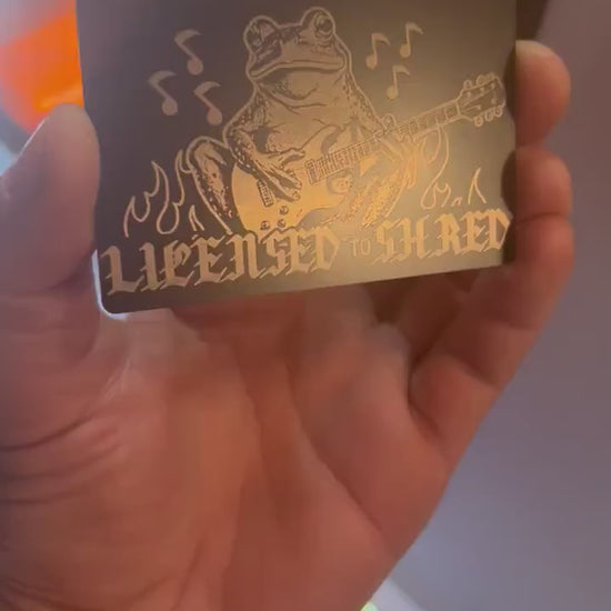 Engraved metal keepsake musician card turning under light to highlight frog guitarist shredder design