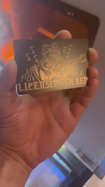 Engraved metal keepsake musician card turning under light to highlight frog guitarist shredder design
