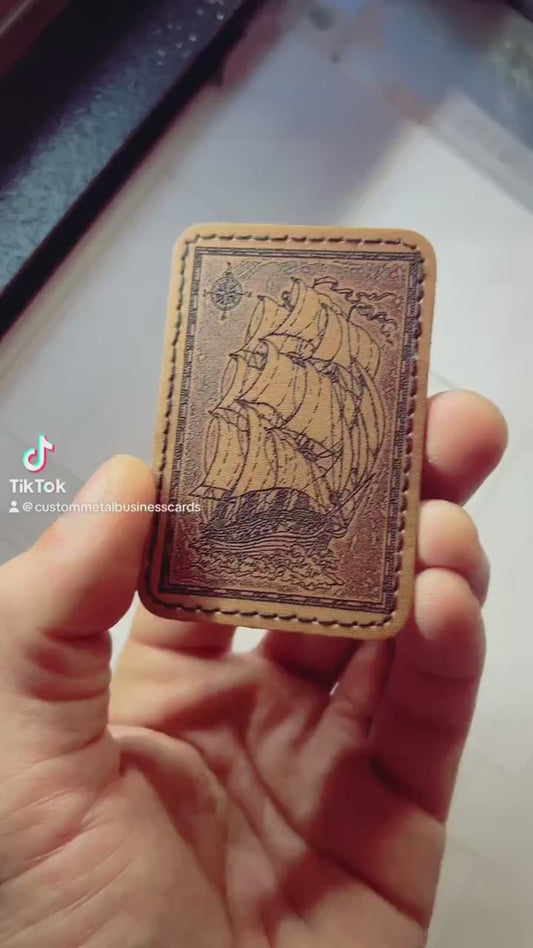 hand holding laser engraved brown leather patch, rotating to demonstrate sailship design