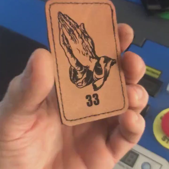 Hand holding brown leather engraved hands praying with angel 33 number design
