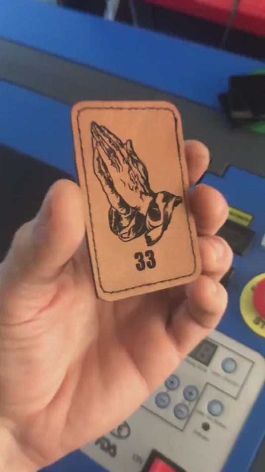 Hand holding brown leather engraved hands praying with angel 33 number design