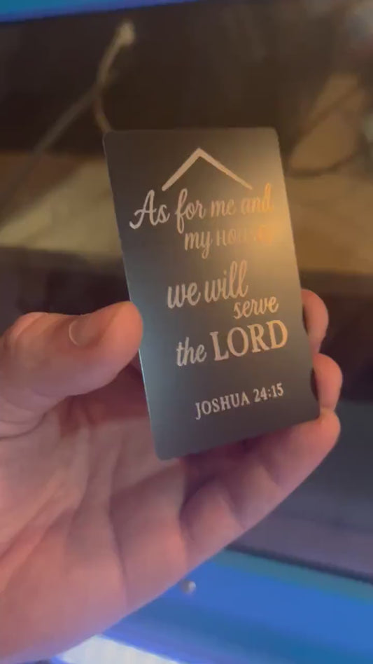 Hand holding a laser engraved metal keepsake card with "As For Me And My House, We Will Serve The Lord" typography text and Joshua 24:15 bible verse reference