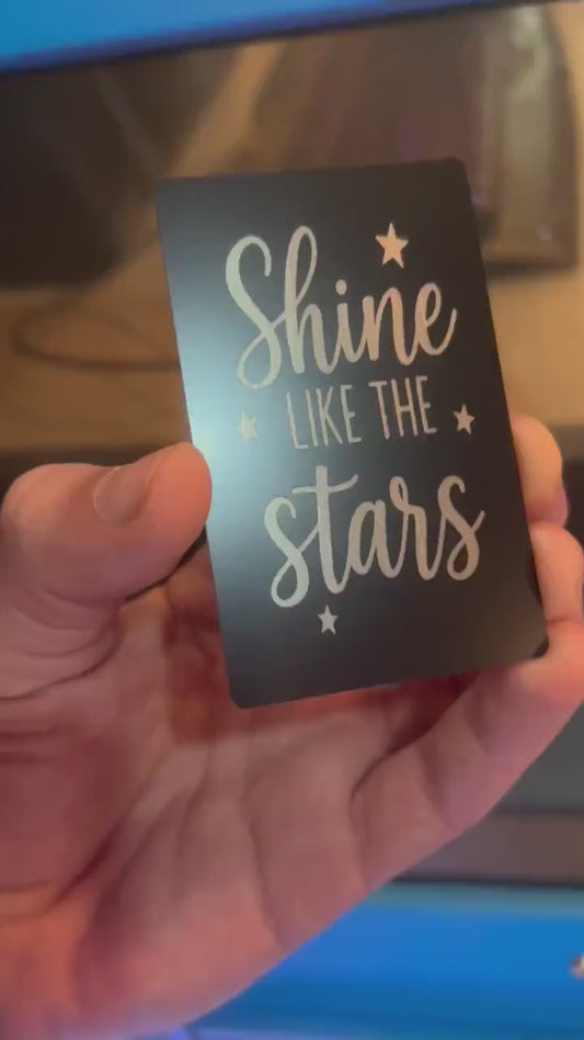 Hand holding a laser engraved black/silver Shine Like The Stars keepsake card