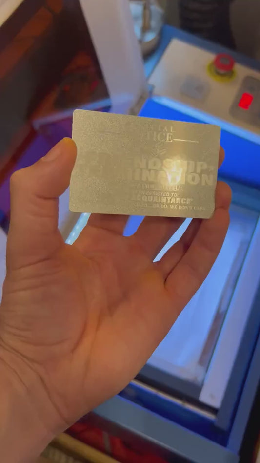 Close up video of hand holding a laser engraved metal gift card with Friendship Termination funny gag gift card text, in Silver/Silver