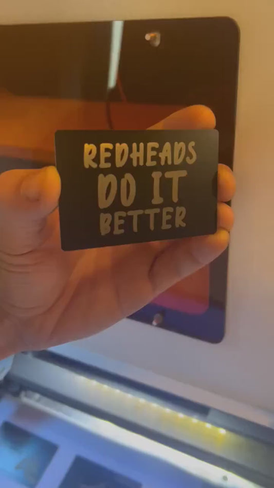 Close up video of hand holding a laser engraved funny metal gift card with Red Heads Do It Better sarcastic text