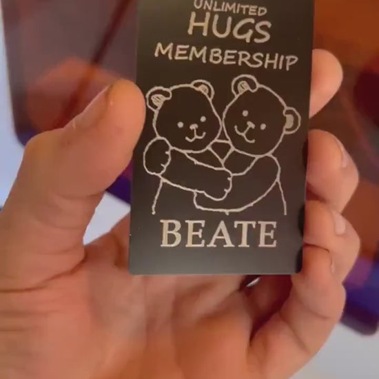 Hands rotating personalized metal Unlimited Hugs Membership card to display engraved name