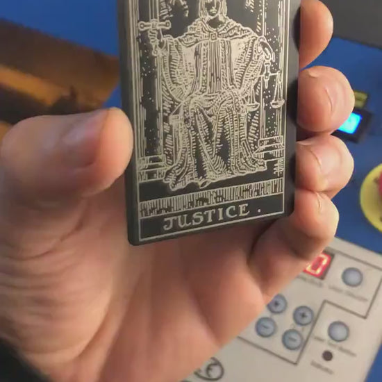 Close-up video of laser engraved metal Justic tarot card rotating to show shine and detail