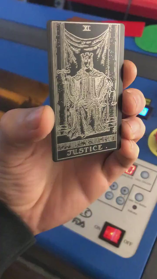Close-up video of laser engraved metal Justic tarot card rotating to show shine and detail