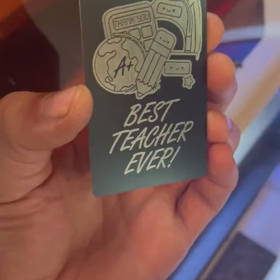 Close-up video of black anodized metal card rotating to show laser engraved best teacher ever artwork and design