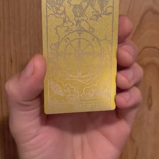 Hands rotating personalized metal tarot card to display engraved wheel of fortune design