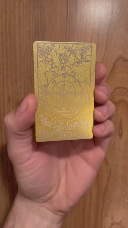 Hands rotating personalized metal tarot card to display engraved wheel of fortune design