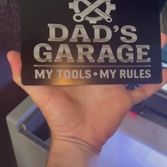 Hands rotating 5x7 metal plaque that reads "Dad's garage"