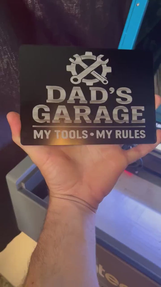 Hands rotating 5x7 metal plaque that reads "Dad's garage"