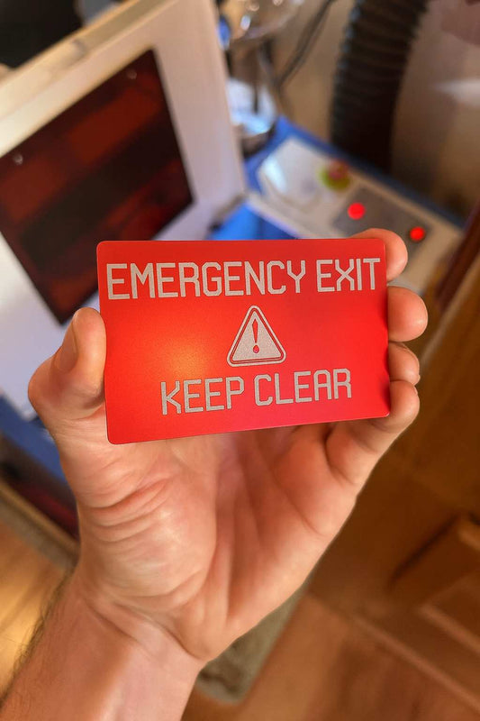 Hand holding a red emergency exit sign with a warning symbol.