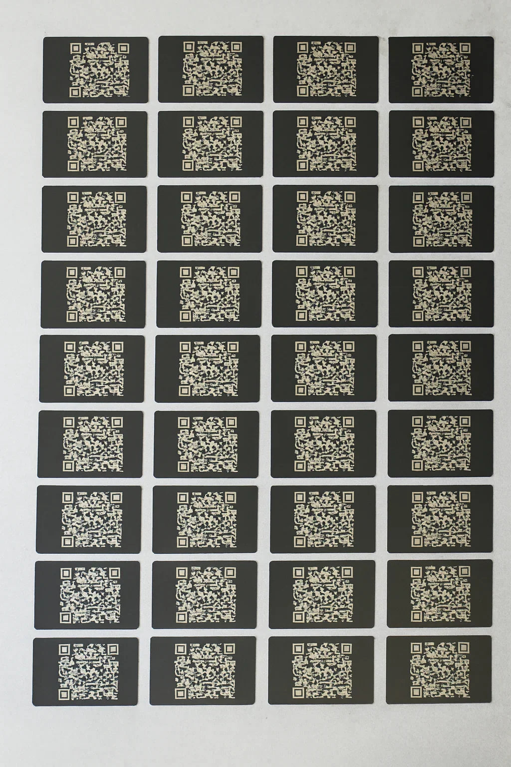 Sheet of QR code metal business cards arranged in a grid on a white background