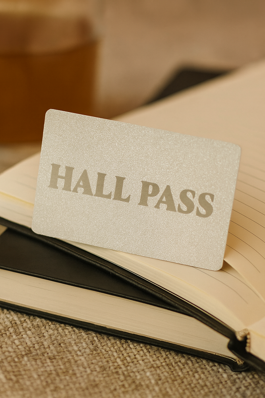 Hall pass metal card on top of an open book with a textured background