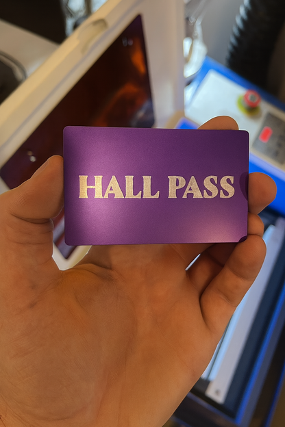 Hand holding a purple/silver 'Hall Pass' card with a blurred background