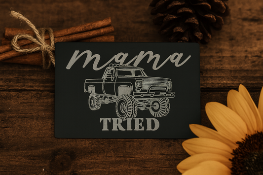 Keepsake card with lifted country truck graphic and 'mama tried' text on a wooden surface with cinnamon sticks and a sunflower.