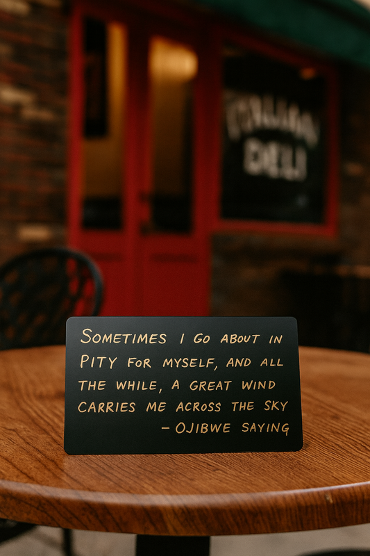 Black plaque with text on a wooden table in a restaurant setting