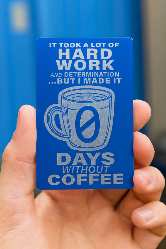 Blue/silver metal card with coffee mug graphic and text about coffee dependence held by a hand.