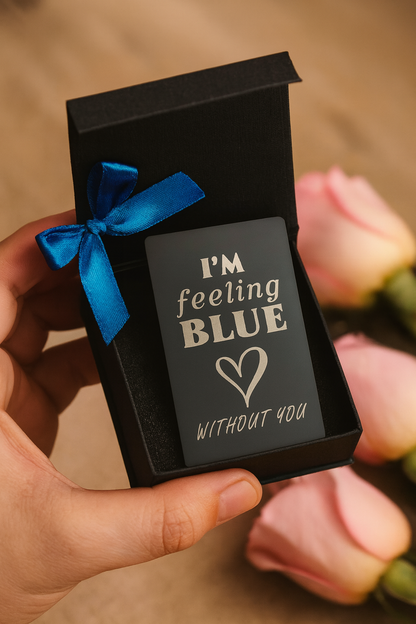 'I'm feeling BLUE without you' message,  engraved in metal keepsake held by a hand with flowers in the background.